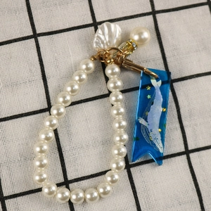 Detail of DIY bookmark kit featuring white pearls, blue resin pendant, and seashell charms