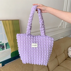 Macro shot of light purple bubble textured fabric and white woven label on the tote bag