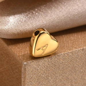 Close-up of heart-shaped gold charm bead with letter A engraving for DIY jewelry