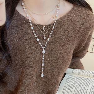 Detailed view of triple-layered gold necklace with pearls and star moon pendants