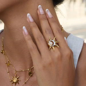 Detail of sun and moon ring with white gemstone and matching gold celestial necklace