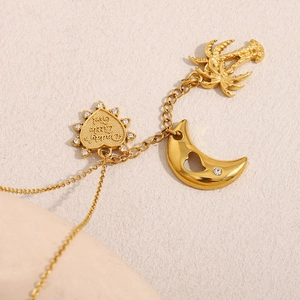 Dettaglio di ciondoli a cuore e palma in oro 18K su una catena in acciaio inossidabile
