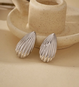 Macro shot of silver teardrop stud earrings with elegant vertical striped texture