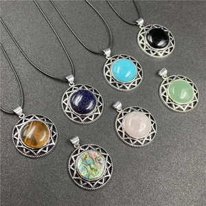 Assorted circular gemstone necklaces with starburst metal pendants on dark background