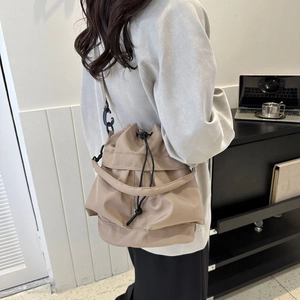 Détail d'un sac seau kaki à cordon et bandoulière en nylon ajustable sur un mannequin