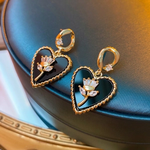 Elegant gold-edged black heart earrings with crystal floral inlay on leather tray