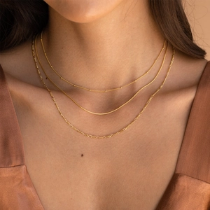 Detailed view of layered 18K gold plated stainless steel necklaces on a female neck