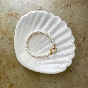 Elegant natural freshwater pearl bracelet with golden sailor clasp on white shell tray