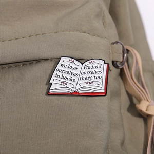 Enamel book brooch with literary quote pinned on green canvas bag for book lovers