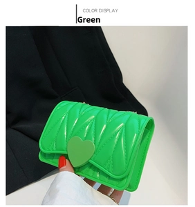 Detail of green silicone heart bag featuring V-shaped quilting and gold chain strap