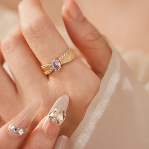 Detail einer goldenen Schleifenring mit ovalem lila Edelstein und Zirkonia auf Modellhand