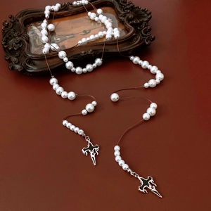 Detail of gothic silver cross pendant with white pearls on a dark vintage leather surface