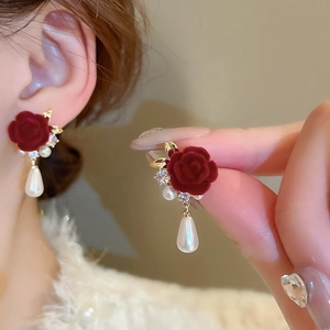 Dettaglio di orecchini festivi con rose in velluto rosso perle e cristalli