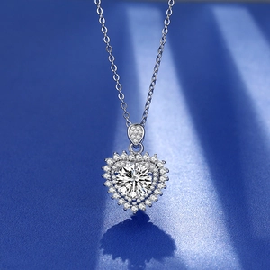 Macro shot of a heart-shaped silver necklace featuring a large brilliant-cut center stone