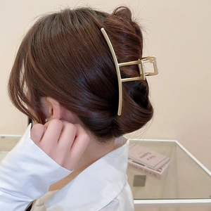 Golden irregular geometric hair claw clip shown in a stylish updo on a female model