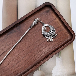 Close-up of vintage silver hair pin with floral hollow carving on dark wood tray