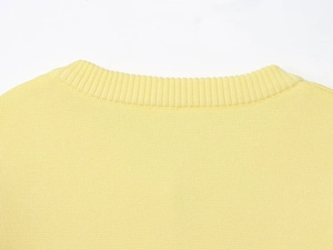 Detail shot of the ribbed crew neck on this light yellow knit sweater with fine texture