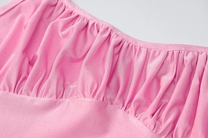 Detail of pink backless dress showing refined pleats and shiny elastic fabric texture