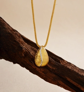 Macro detail of brushed gold teardrop pendant with intricate honeycomb cutouts