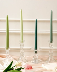 Detalle de velas cónicas verdes en elegantes portavelas de cristal con decoración de tulipa