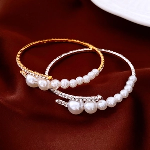 Detail of elegant open bracelets with diamonds and pearls in gold and silver finish