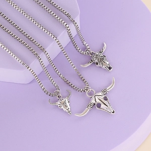 Three vintage silver bull head pendants with box chains on a purple backdrop