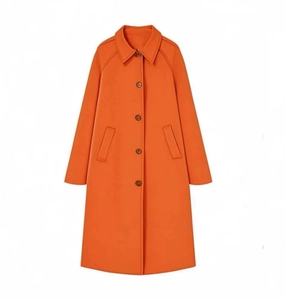 Detail eines leuchtend orangen langen Trenchcoats mit Reverskragen und Knöpfen