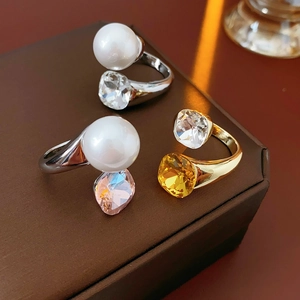 Detailed view of pearl and faceted crystal rings displayed on a brown jewelry box