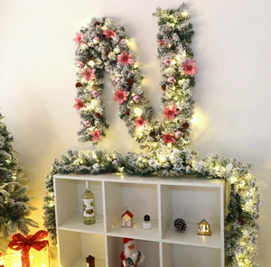 Close-up of 2.7m flocked Christmas garland with pink flowers, silver baubles and warm LED lights