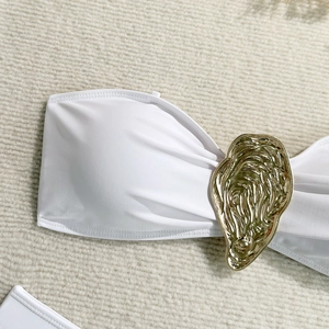 Detailed close-up of white bandeau bikini top with abstract golden metal hardware accent