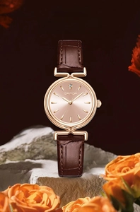 Detail of rose gold vintage watch with brown leather strap displayed on a white stone