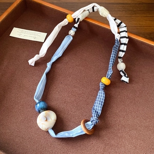 Detail of handmade fabric heart necklace with striped patterns and colorful beads