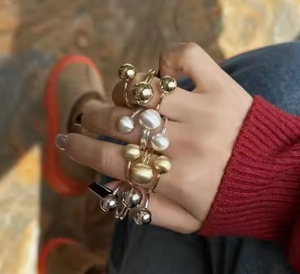Detalle de anillos minimalistas de cuentas de oro y plata con perlas en la mano