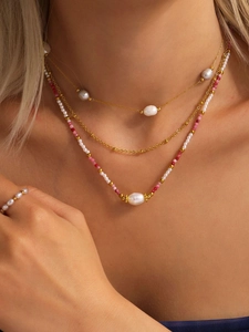 Vista dettagliata della collana dorata multistrato con perle e perline rosa su modella
