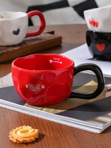 Detail of red ceramic heart mug featuring black handle and Love engraving inside rim