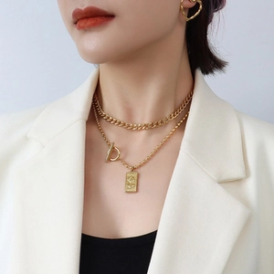 Model wearing a layered 18k gold plated emerald zircon pendant with heart earrings