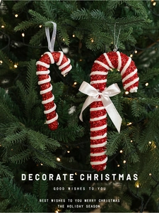 Detail of red and white striped candy cane ornament with sequins on Christmas tree
