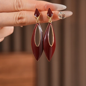 Detail shot of vintage red enamel teardrop earrings with elegant golden metal borders