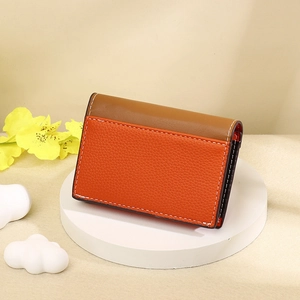 Detail of orange and brown PU leather card wallet with lychee texture and white stitching