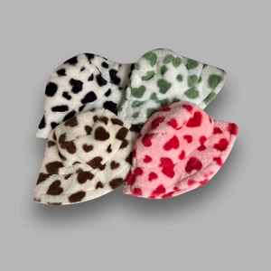 Pile of plush bucket hats in black, green, brown, and pink with heart pattern prints