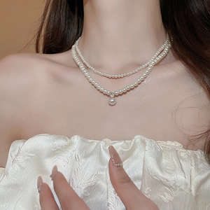 Close-up of double-layer pearl necklace with a sparkling zircon pendant on a model