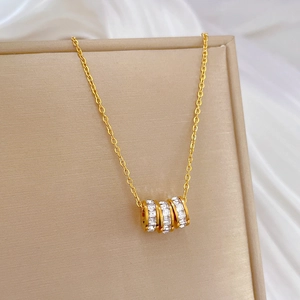 Detailed macro view of triple-ring gold pendant with sparkling pavé crystals on a tray