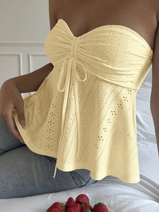 Detail of light yellow lace tube top with delicate hollow patterns and front drawstring tie