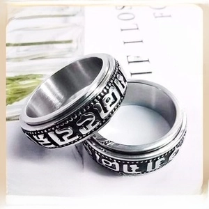 Close-up of stainless steel spinning ring with black enamel band and religious engraving