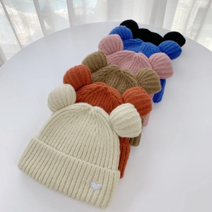 Close-up of colorful bear ear knit beanies with sequined heart patches and warm texture