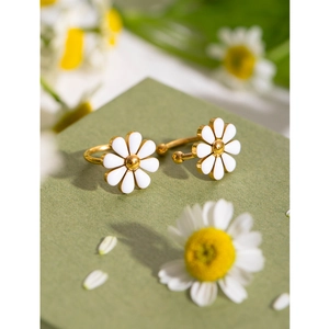 Macro shot of 18k gold plated stainless steel daisy earrings with white enamel petals
