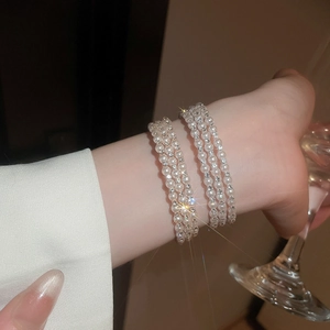 Detail of multi-layer pearl bracelet with sparkling rhinestone rings on wrist