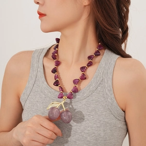 Close-up of purple beaded necklace with sparkling cherry pendant on a fashion model
