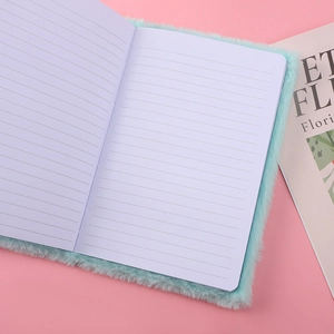 Cute mint green plush cat notebook with white lined pages on a pink background