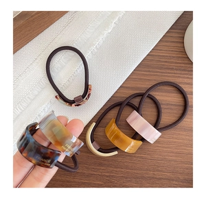 Close-up of handmade acetate hair ties in tortoise and amber colors on a wooden table